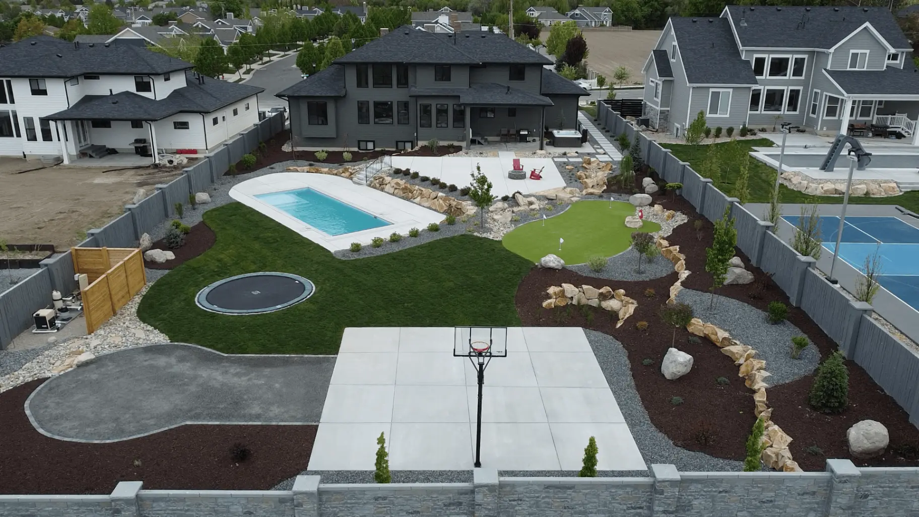 Architectural landscape design with pool, putting green, and stonework by Scenic View Landscape